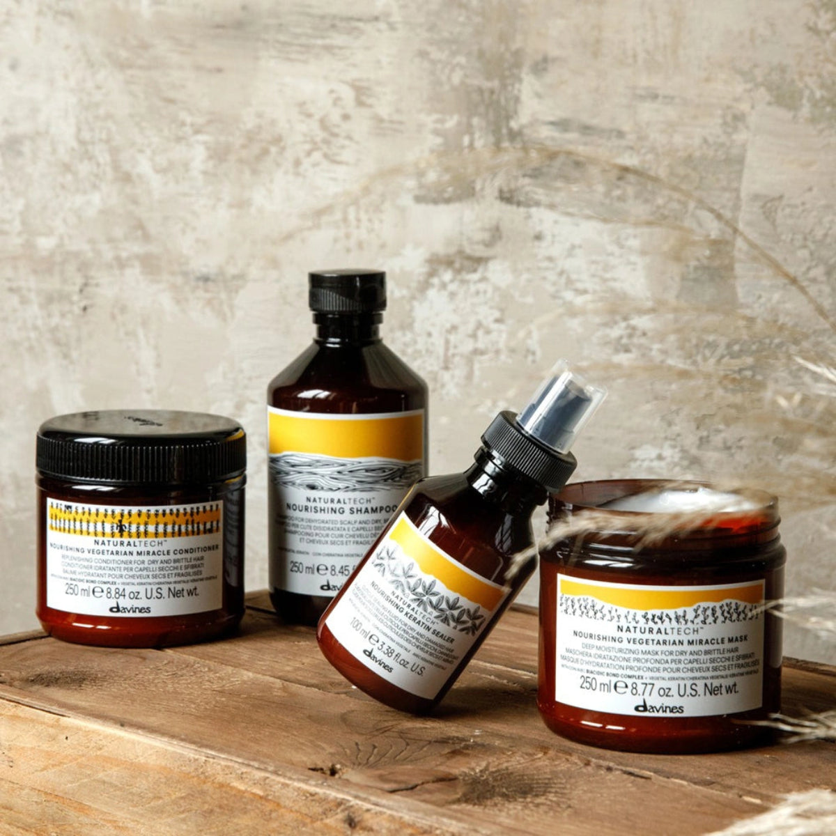 Set of Davines hair care products on a wooden surface with a textured wall background